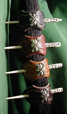 Leather hair barrettes shown in black, chestnut, dark tan and dark brown leathers with hand-carved bone stick and Italian nickel-silver ornament.