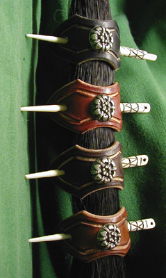 Leather hair barrettes shown in black, chestnut, dark brown and dark tan leathers with hand-carved bone stick and Italian nickel-silver ornament.